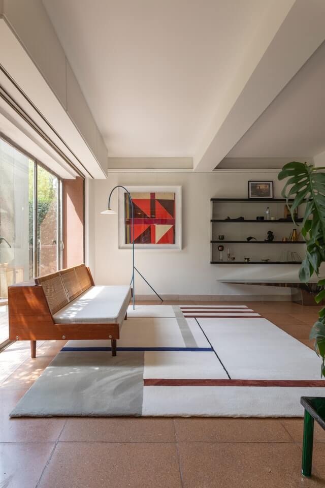 Residential living room. There is a wooden sofa and a massive rug on the floor