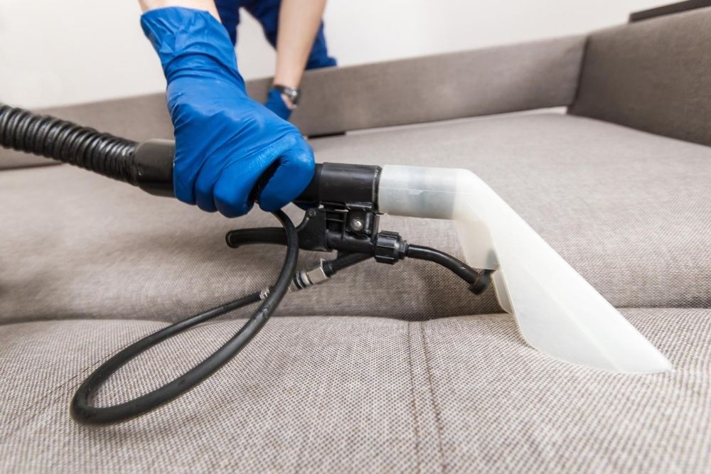 Shot of a upholstery steam cleaning machine head holded by a person with blue gloves