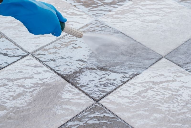 Person using a hose for cleaning a ceramic tile floor