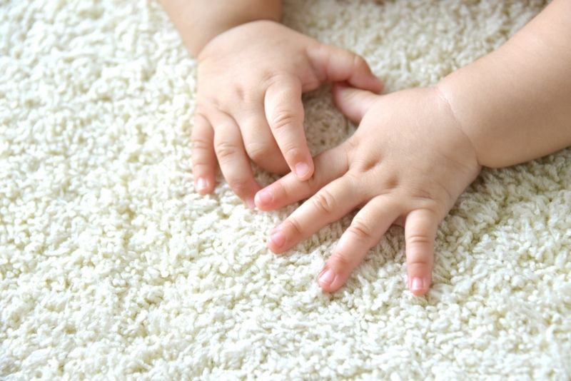 a baby hands on a lean white carpet